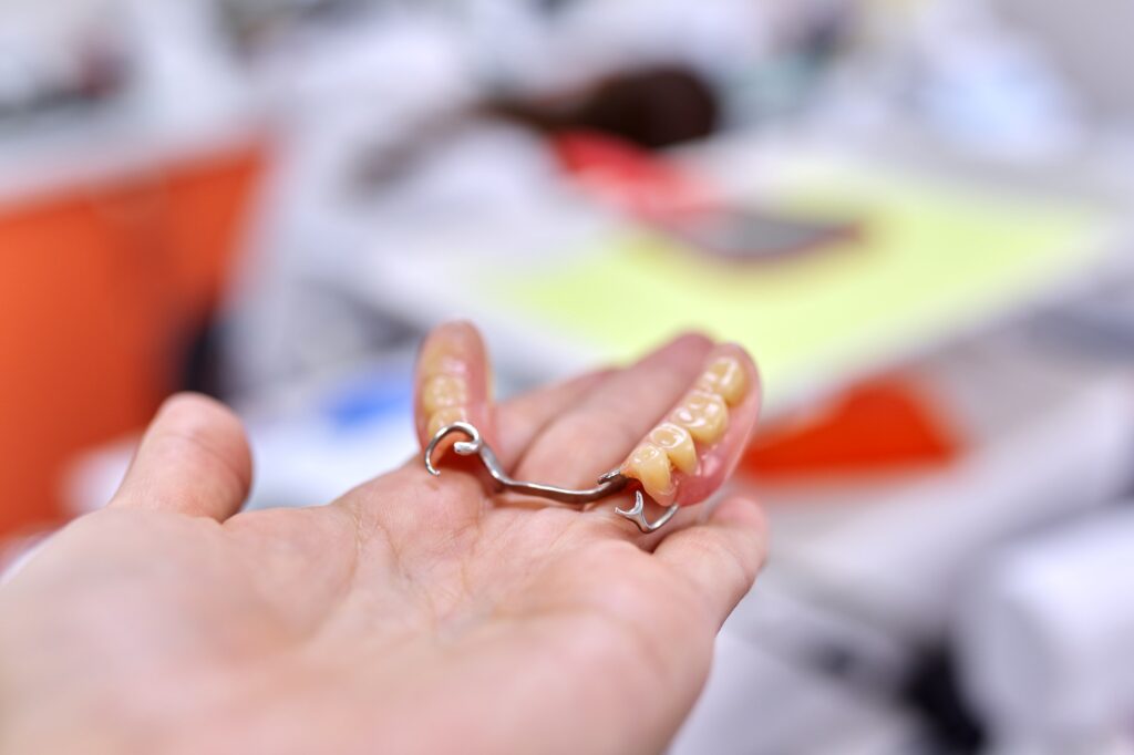 dental implant model dental bridge in hand dentist office background 1024x682 1